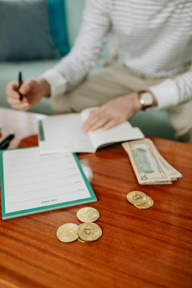 Personne notant des dépenses dans un carnet à côté de billets et de pièces